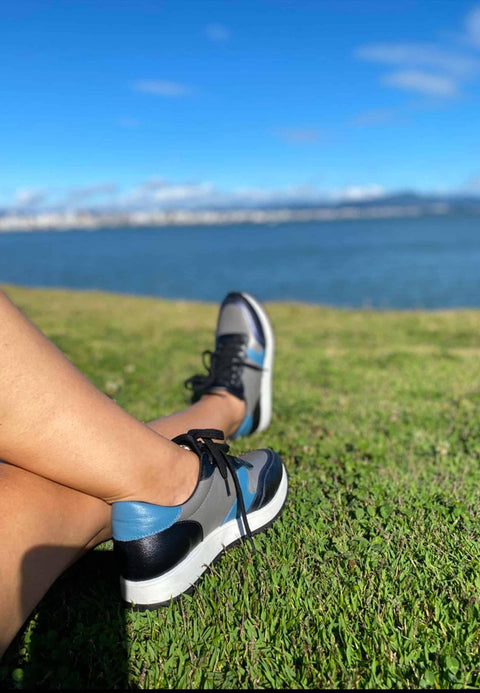3. Women's Mangará Buriri sneakers in grey, blue, and black worn outdoors by a lake