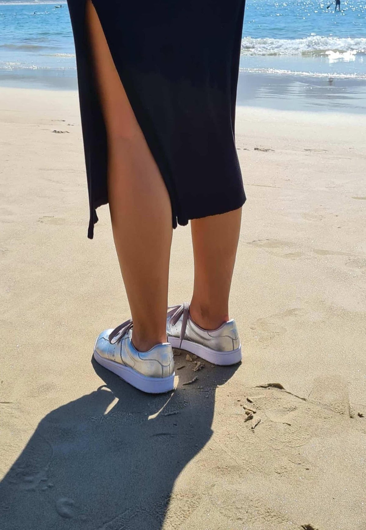 1. Women's Mangará metallic silver leather sneakers worn on beach, showing casual elegance