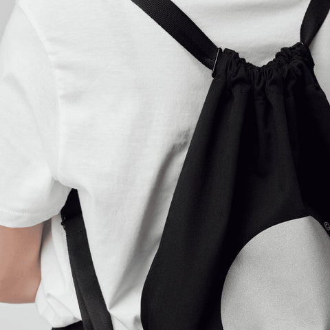 2. Close-up of woman wearing March Design Studio's Water Resistant Reflective Backpack DOT, highlighting reflective circle and drawstring closure