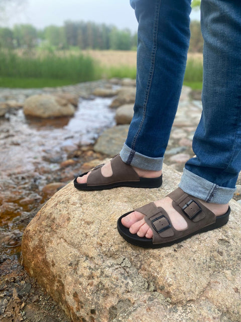 1. Men's dark brown leather sandals by Omaking worn by a model standing on a rock by a stream