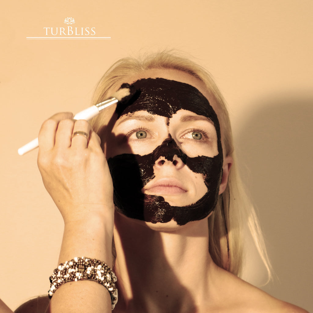 1. Woman applying peat mask with Turbliss vegan mask brush, showcasing smooth application