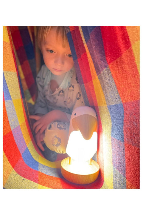 1. Child sitting in colorful tent with pink bird lamp providing soft light