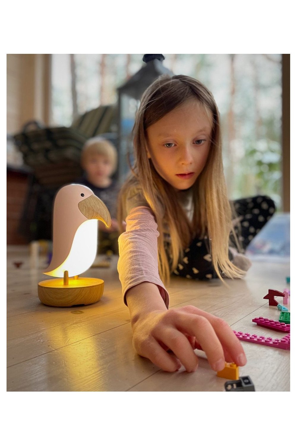 1. Girl playing on floor with pink bird lamp glowing beside her, creating a cozy play environment