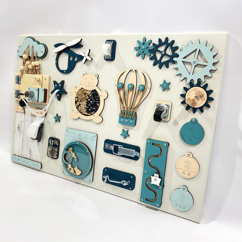 3. Studio shot of Montessori busy board with blue and beige interactive elements like a bear, gears, and locks, designed for sensory play, by BusyBunnyToys.