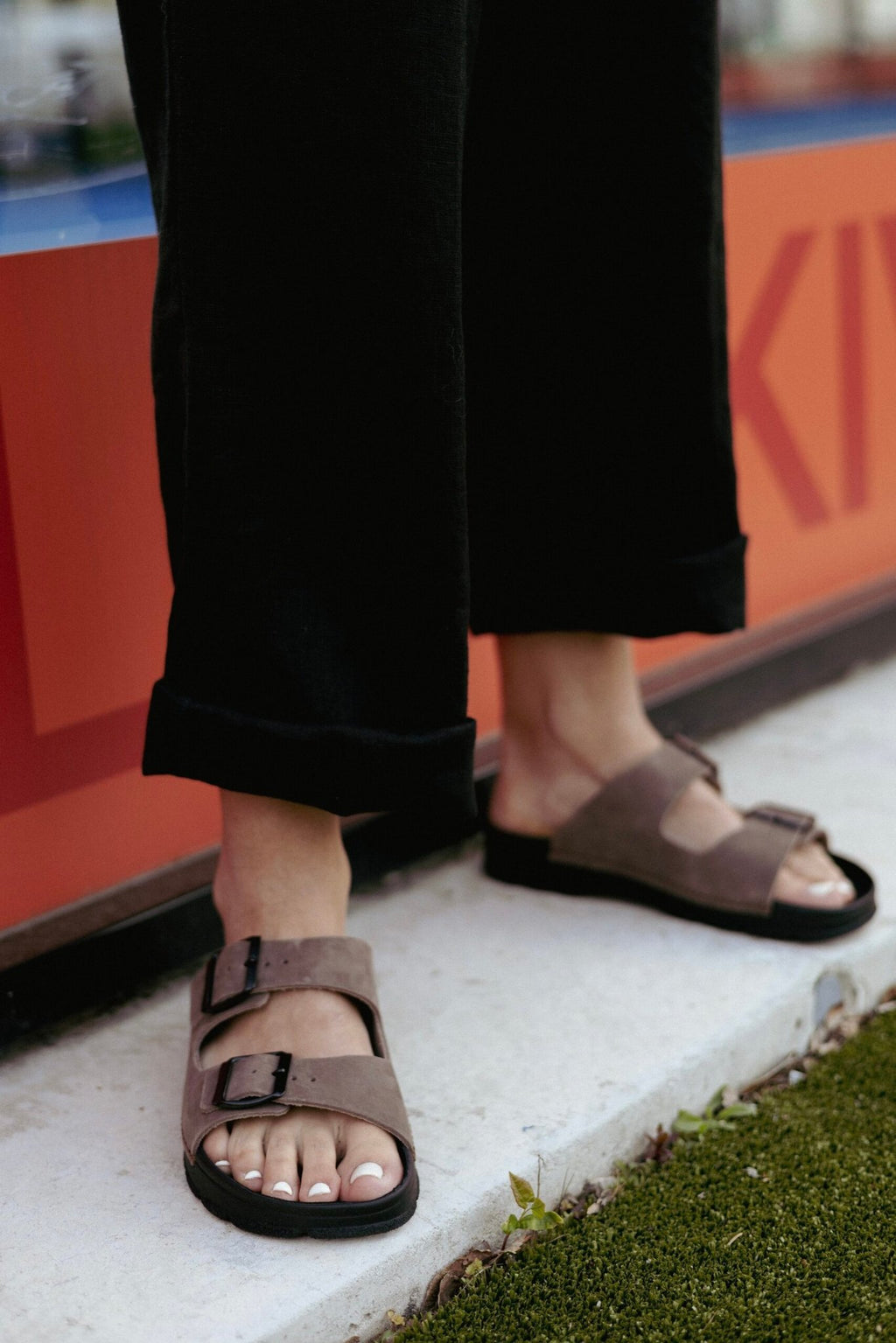 2. Close-up of women's Meeliku leather sandals in brown and black by OmaKing, styled with black pants