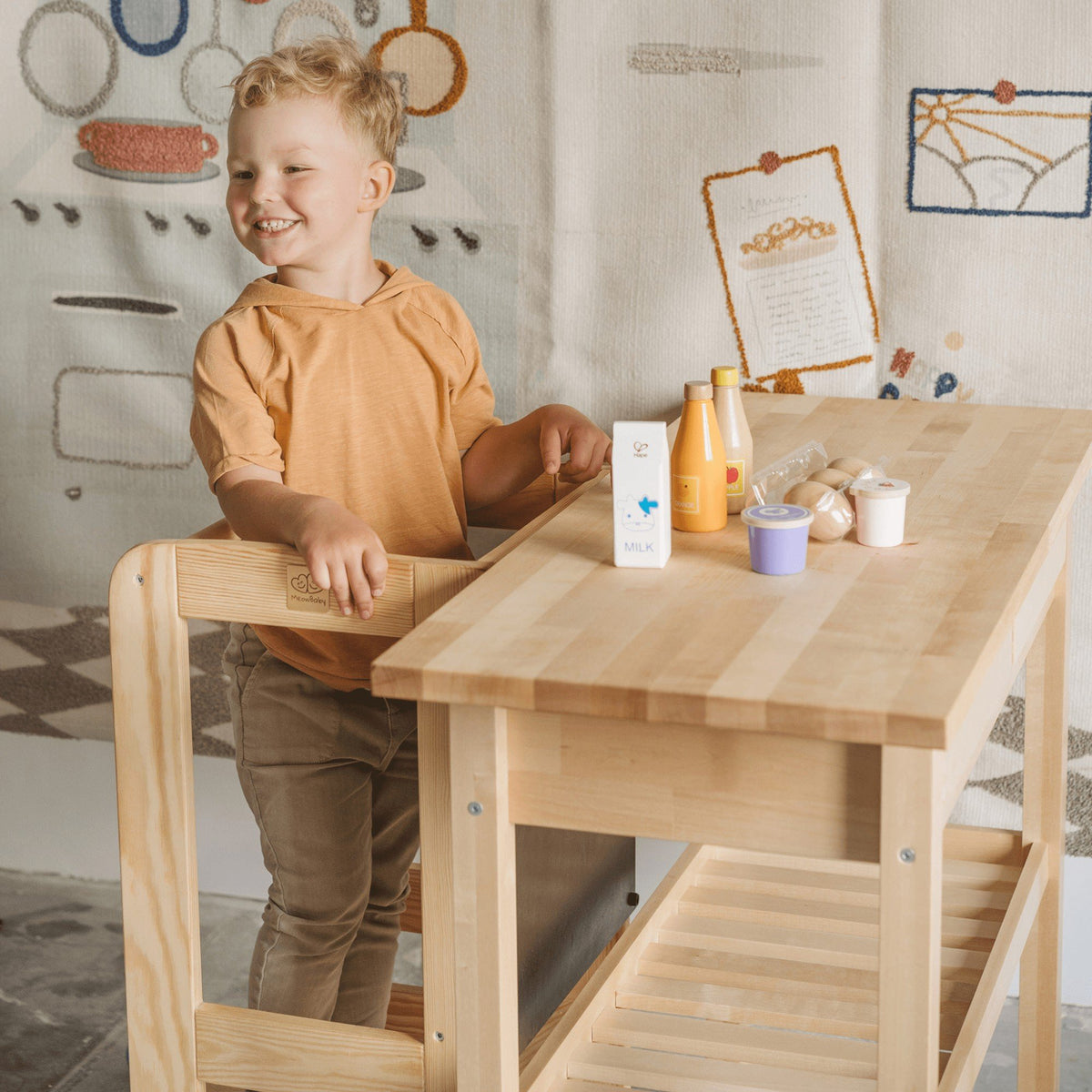 9. Smiling child using MeowBaby kitchen helper at table with toy food items