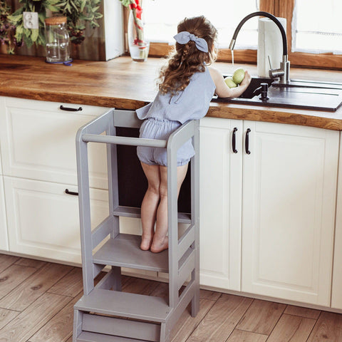 1. Girl reaching sink using dark grey MeowBaby kitchen helper in home kitchen