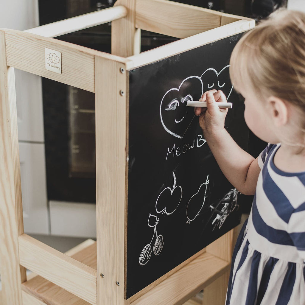 2. Child drawing on blackboard of wooden kitchen helper in natural finish