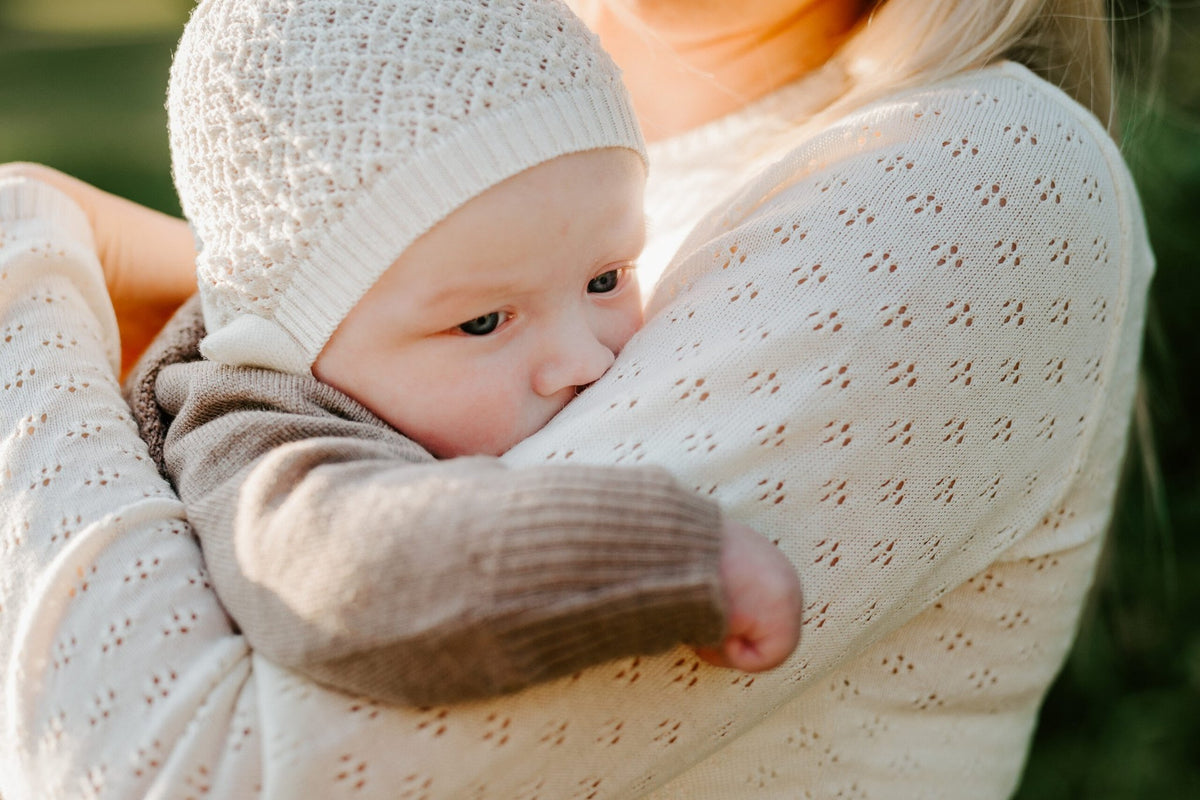 1. Baby held by woman in garden wrapped in white merino wool blanket