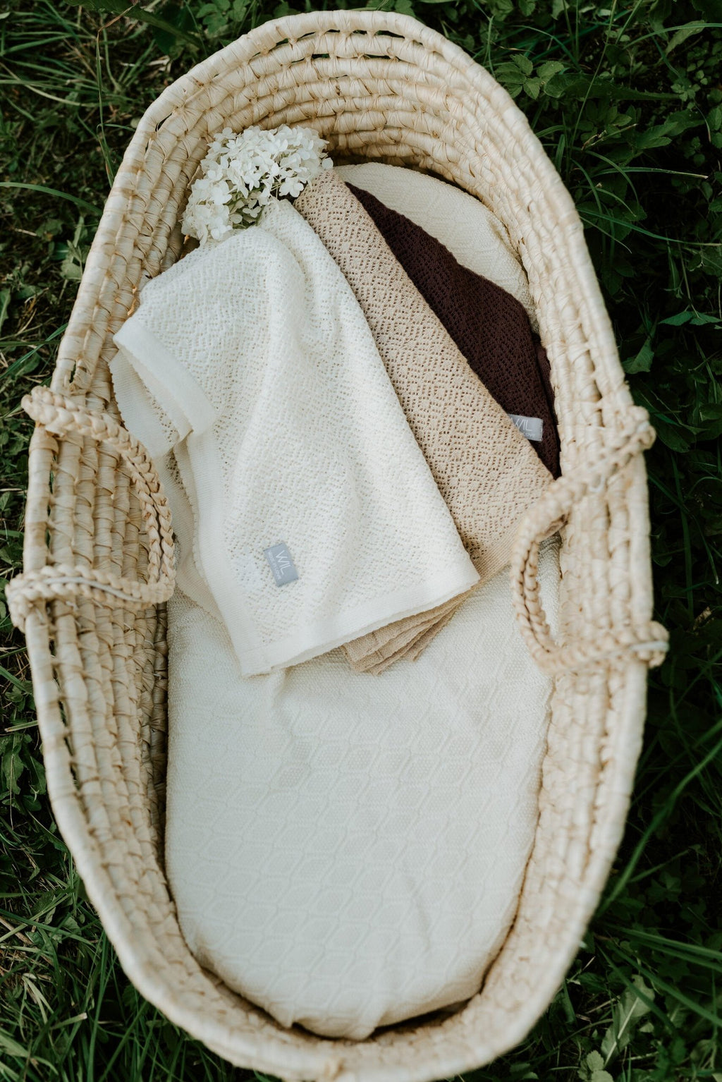 4. Flat lay of white and beige merino wool baby blankets in woven basket on grass
