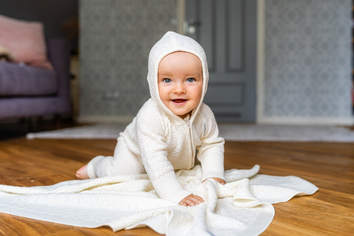 1. Baby in white outfit crawling on merino wool baby blanket in cozy indoor setting