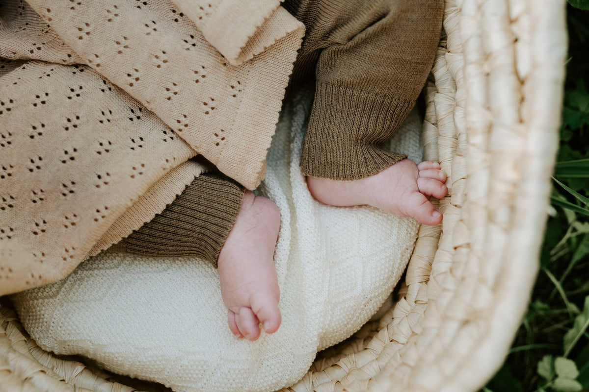 10. Close-up of baby feet under beige merino wool blanket in woven basket