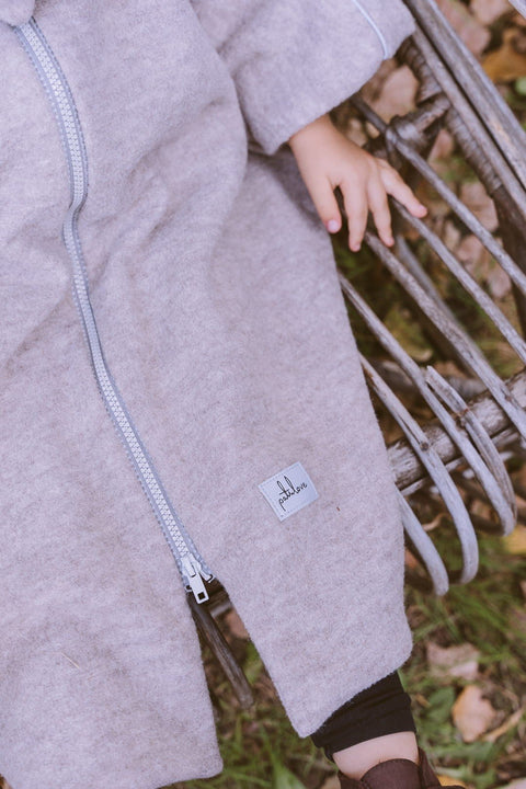 5. Close-up of beige merino wool poncho with Patulove logo on child's lap