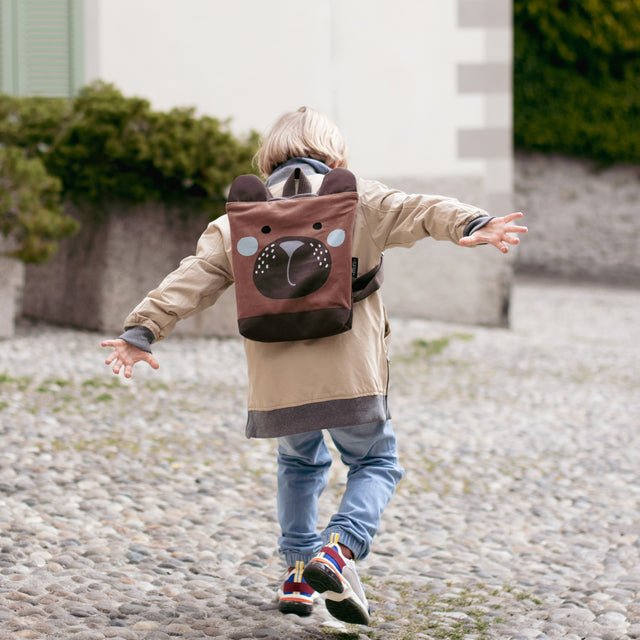 7. Child with Muni bear backpack at a fountain, highlighting playful outdoor use