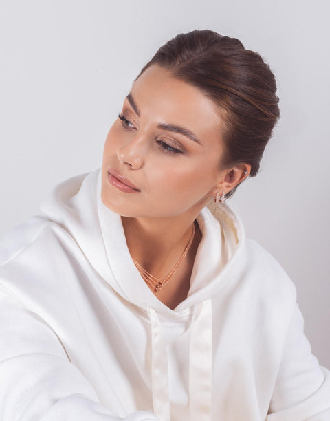 1. Woman wearing rose gold hoop earrings with zircons, styled with white hoodie
