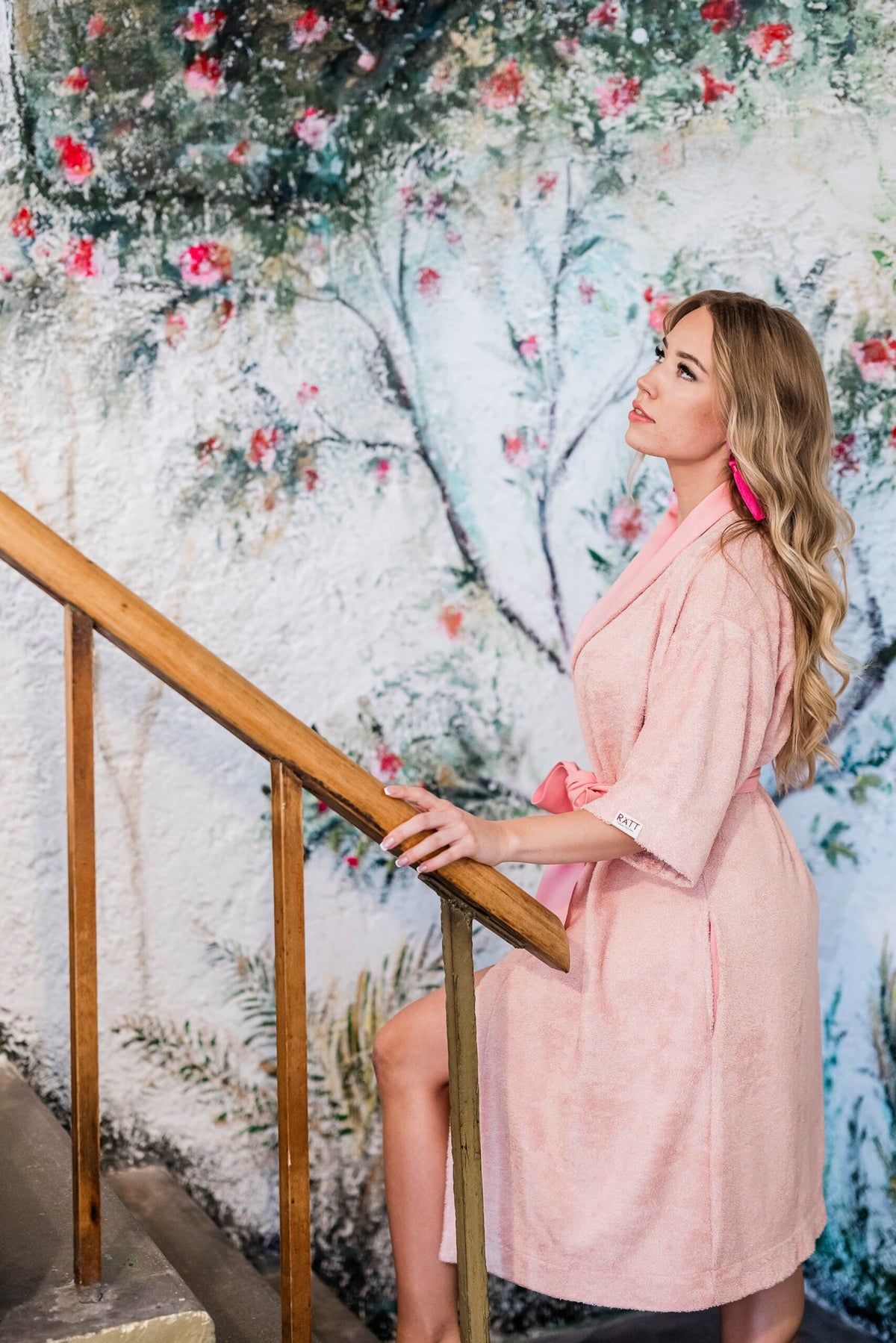 3. Woman in pink bamboo terry robe with shawl collar ascending stairs in floral setting