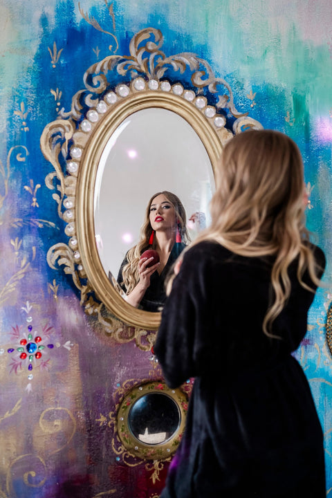 1. Woman in black bamboo terry robe with shawl collar applying lipstick in front of ornate mirror