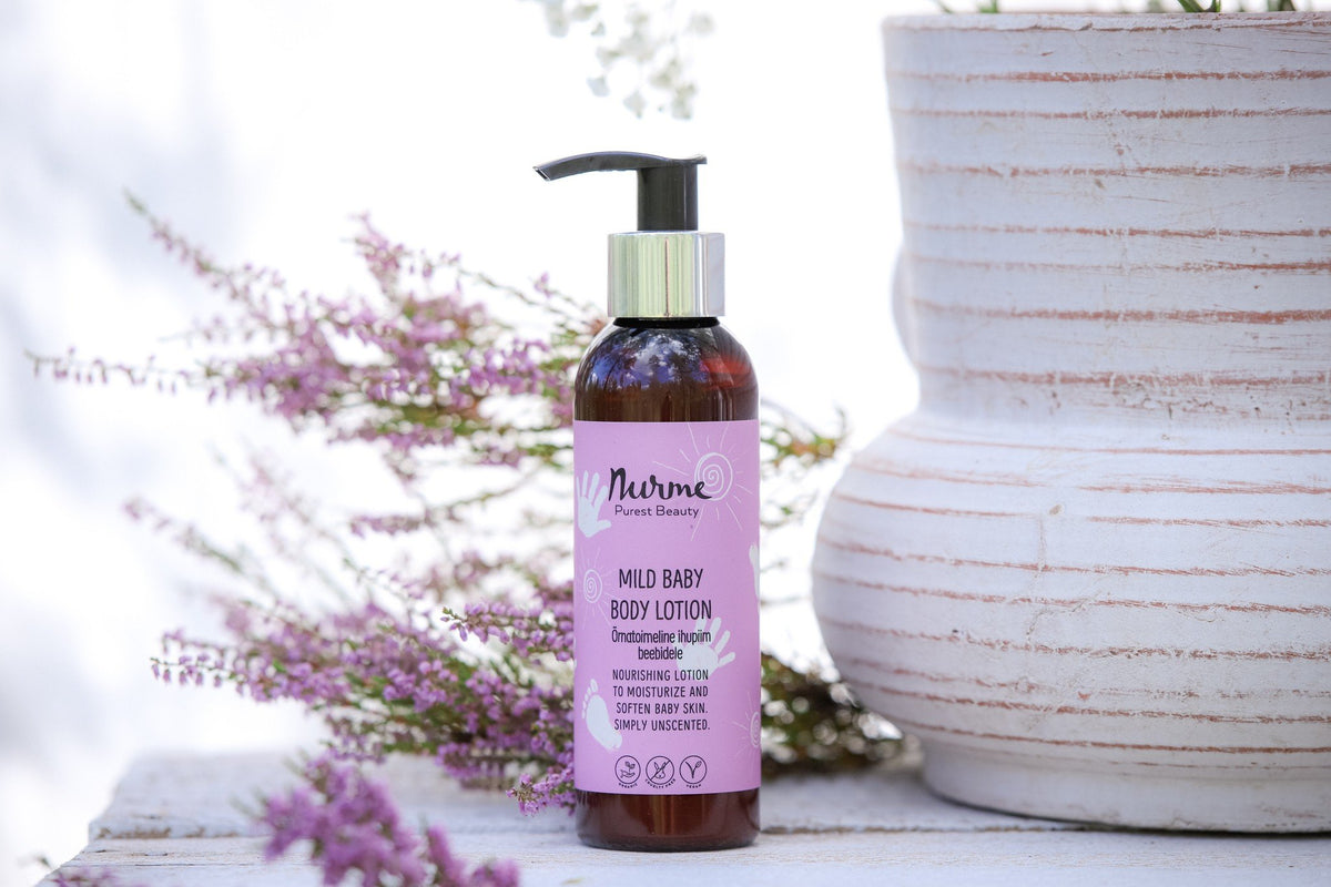 3. Nurme Mild Baby Body Lotion with pink label placed outdoors next to lavender flowers and a white pot