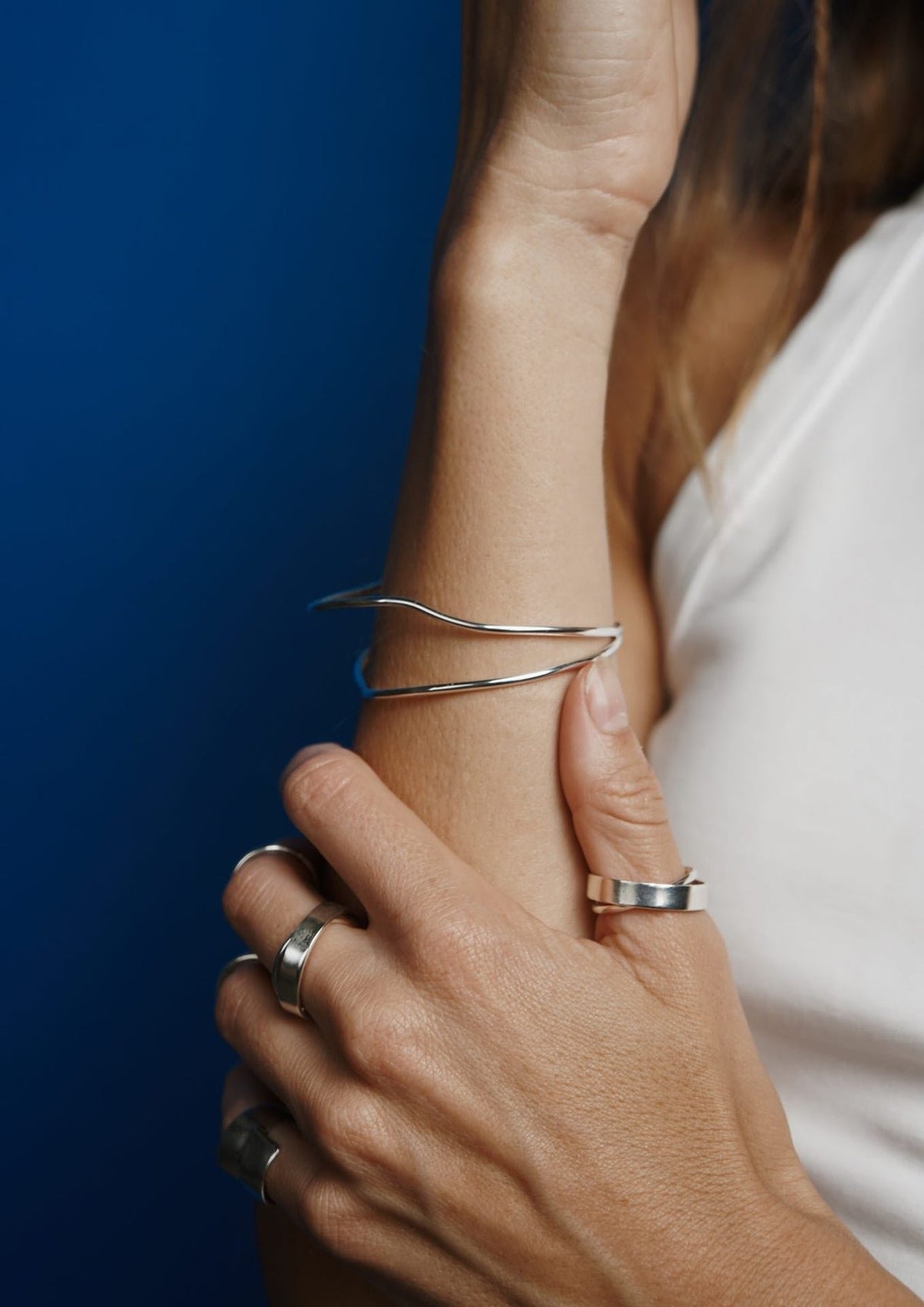1. Woman wearing multiple silver rings including Milky Way ring by NO MORE, with a blue background highlighting the jewelry