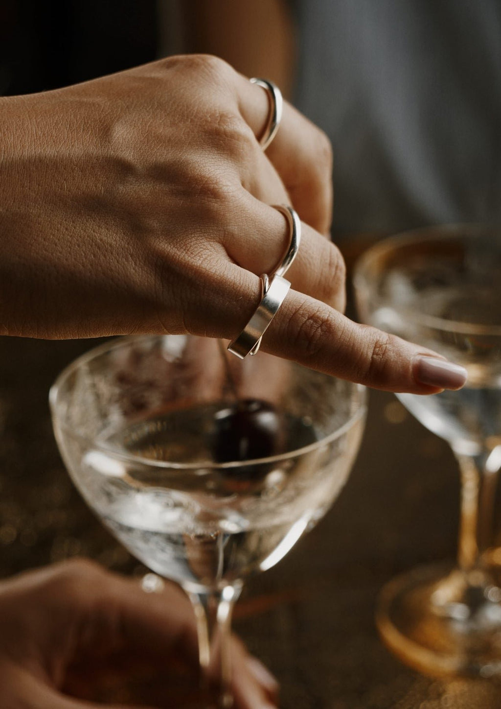 1. Woman's hand wearing Milky Way ring by NO MORE, elegantly holding a glass, highlighting the ring's design