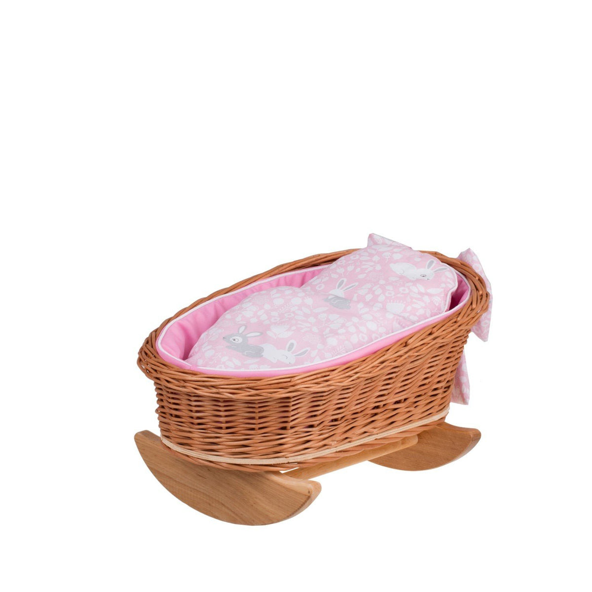 1. Wicker Stories doll cradle made of natural wicker with pink lining, pillow, and duvet featuring rabbit print, on wooden rocking runners, studio setting