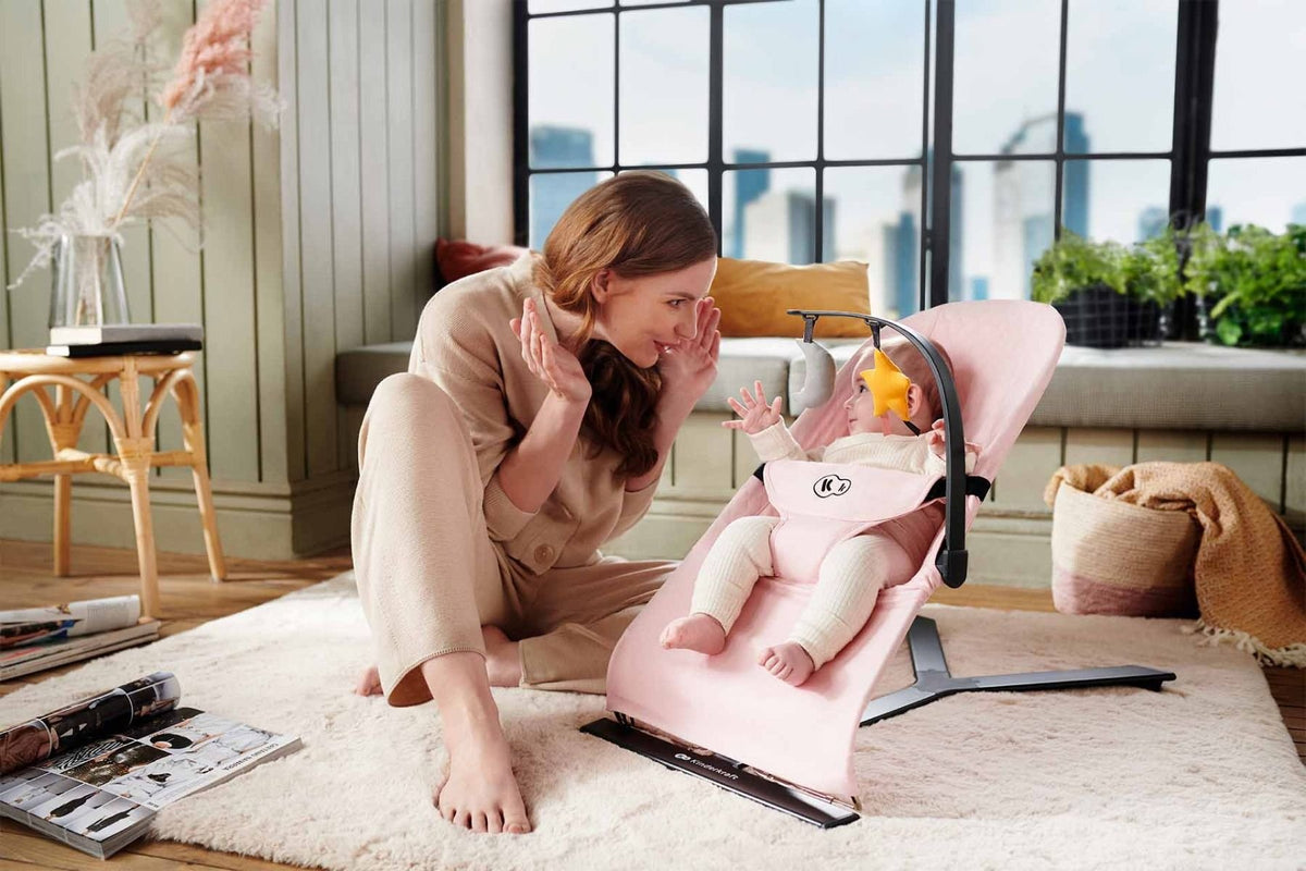 1. Woman interacting with baby in beige Kinderkraft MIMI bouncer in cozy living room setting