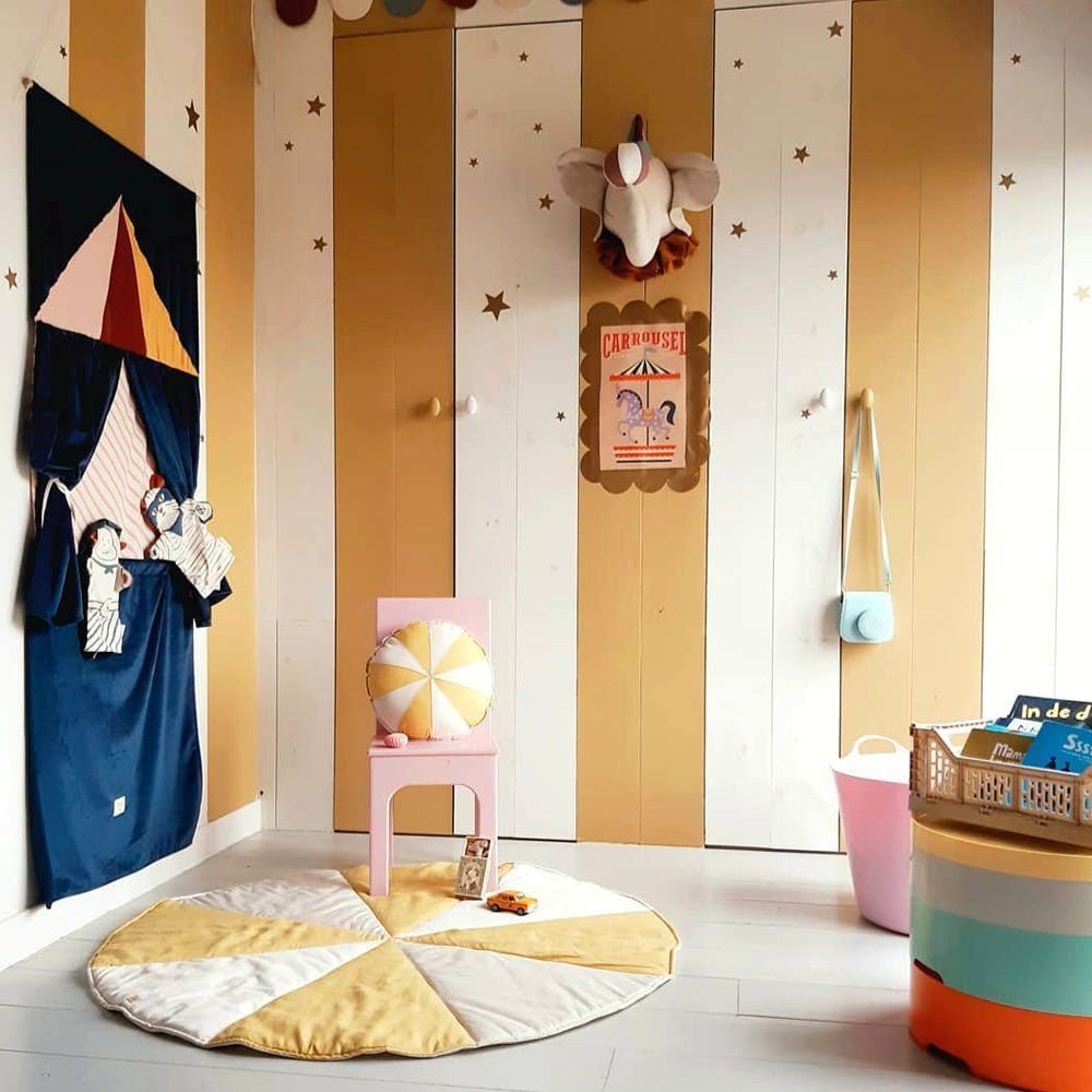 7. Playroom with gold star wall stickers, striped walls, and colorful decor