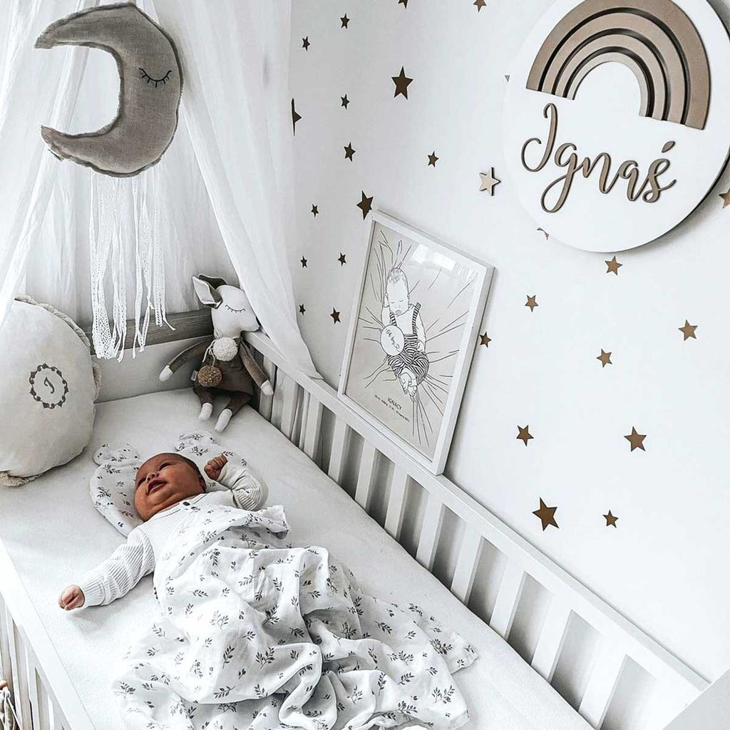 4. Nursery with gold star wall stickers, baby in crib, and personalized rainbow decor