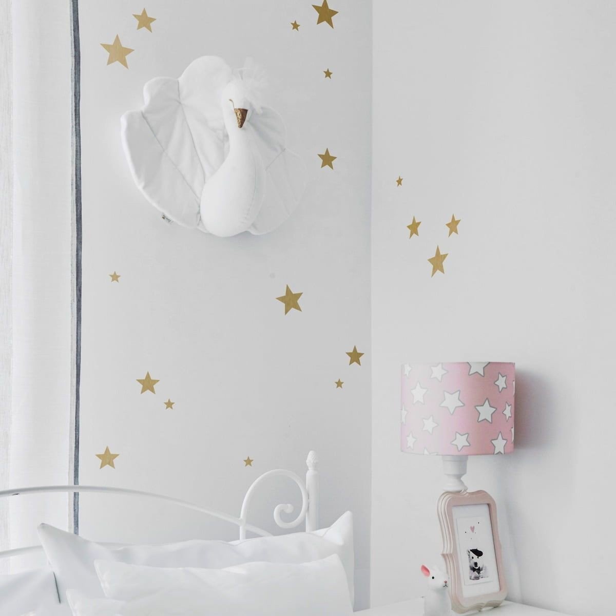 1. Children's room with gold star wall stickers, white bed, pink star lamp, and swan wall decor