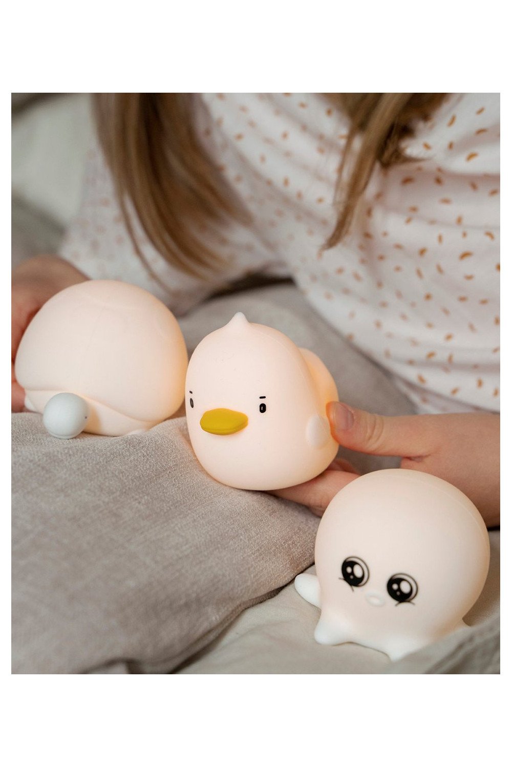 7. Child holding duck and turtle shaped silicone lamps with octopus lamp on bed