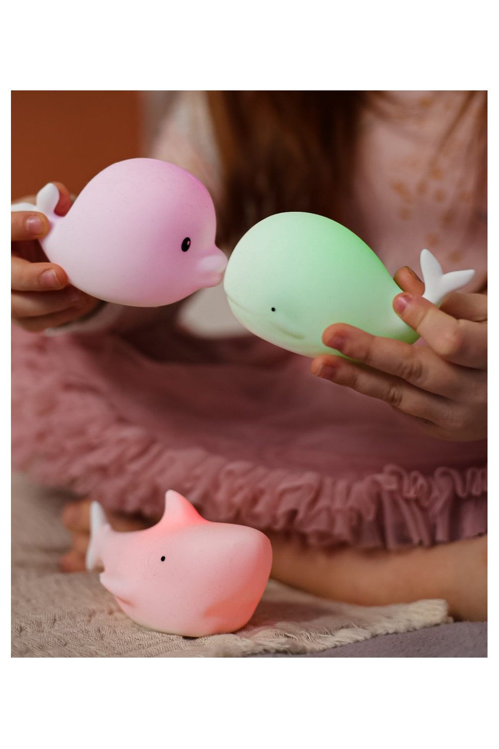 1. Child holding glowing Dolphin and Whale silicone lamps with Shark lamp on the floor, showcasing color-changing feature
