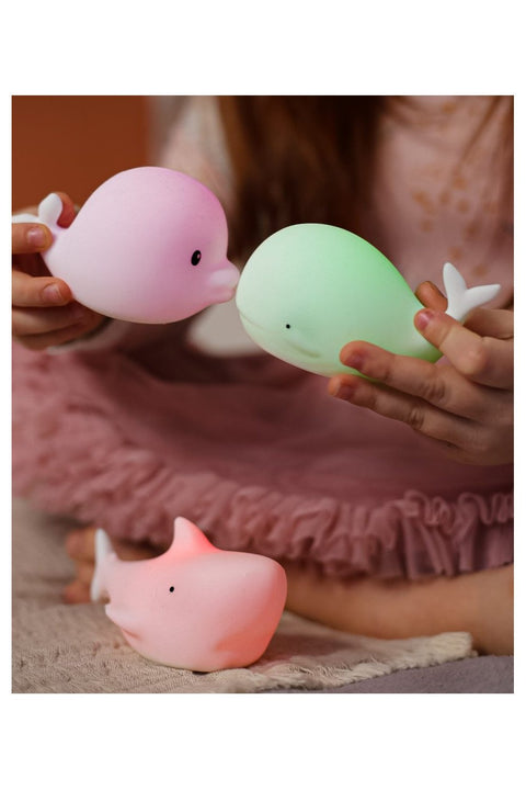 1. Child holding glowing Dolphin and Whale silicone lamps with Shark lamp on the floor, showcasing color-changing feature