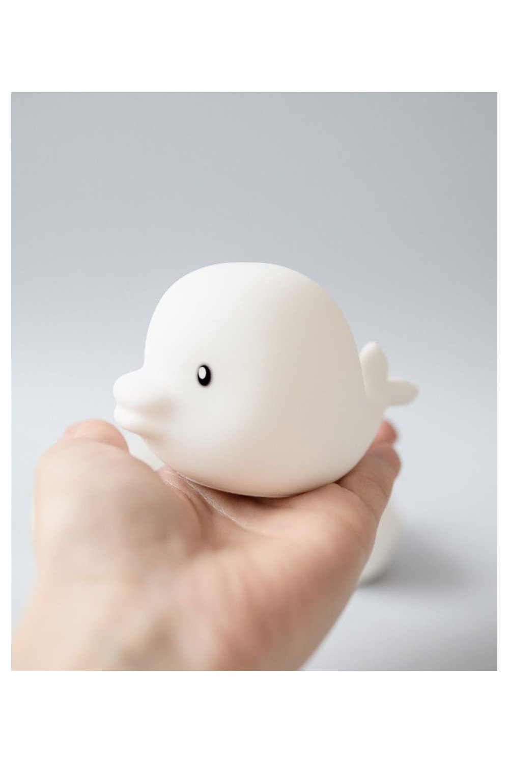 3. Close-up of a white silicone Dolphin lamp held in a hand, highlighting soft texture and compact size