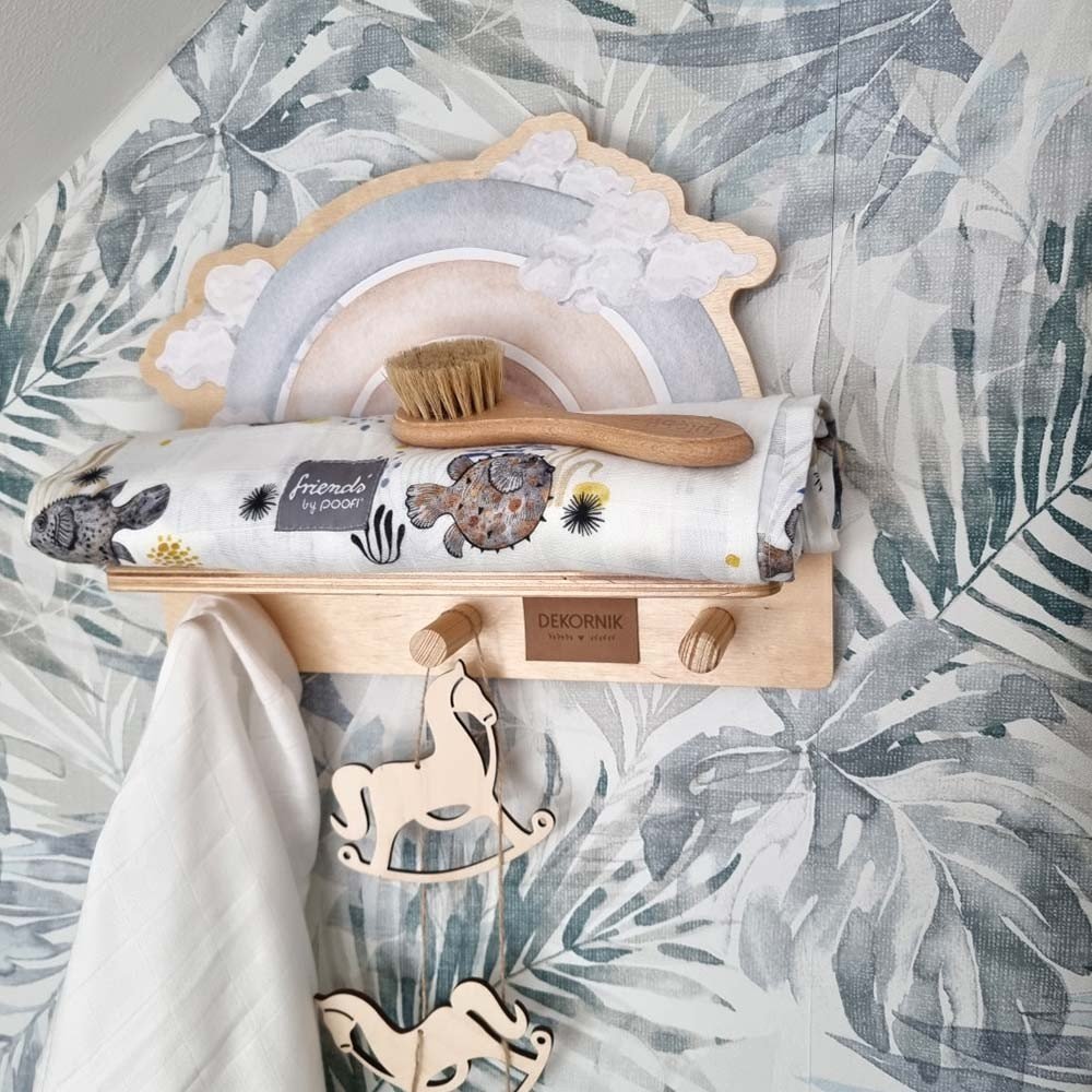 6. Mini wall shelf with blue rainbow design in a nursery, holding a brush and hanging wooden horse decor