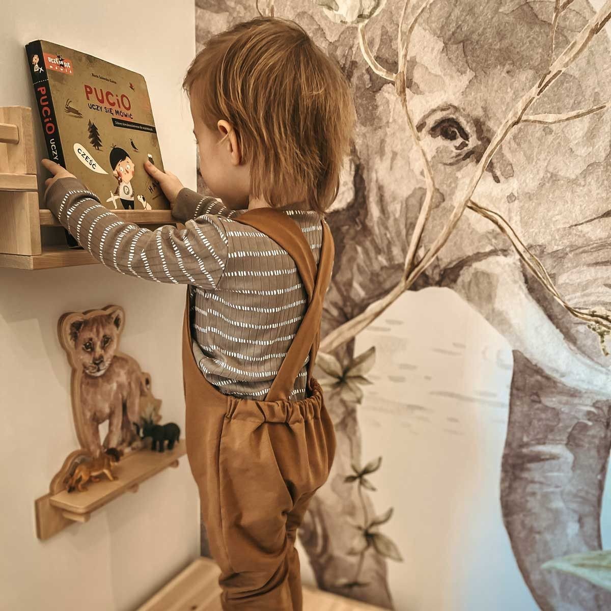 1. Child reaching for a book on a shelf with Dekornik mini wall shelf featuring lion design in a playroom