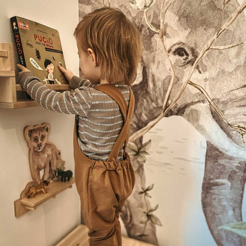 1. Child reaching for a book on a shelf with Dekornik mini wall shelf featuring lion design in a playroom