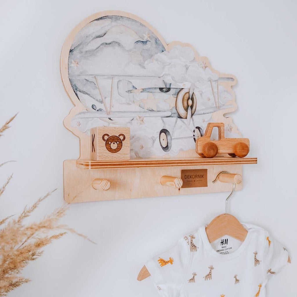 1. Children's room with Dekornik mini wall shelf featuring a plane design, wooden toys, and a hanging baby outfit