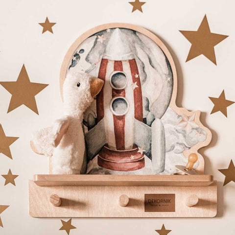 2. Rocketship mini wall shelf with plush toy and wooden pegs, surrounded by star decals, in a playful nursery setting.
