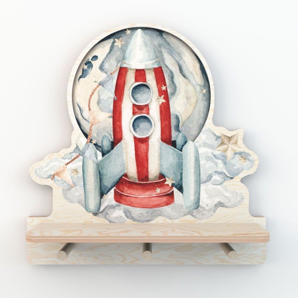 5. Studio shot of rocketship mini wall shelf with colorful design and three pegs, on a white background.