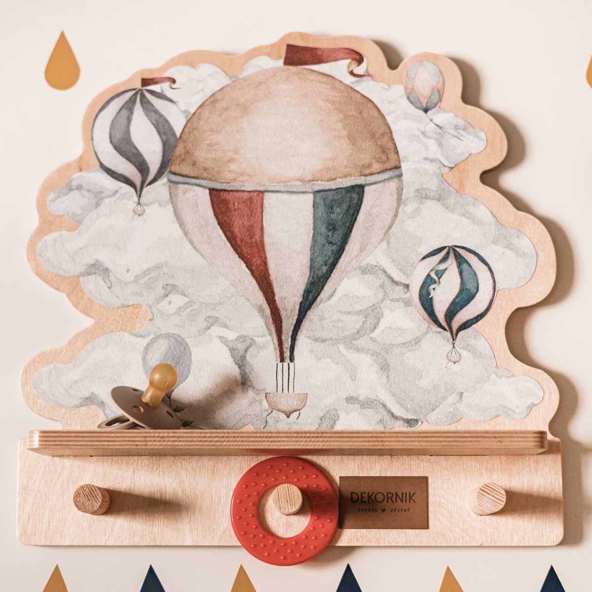 2. Close-up of mini wall shelf with hot air balloon design, holding a pacifier and red teething ring