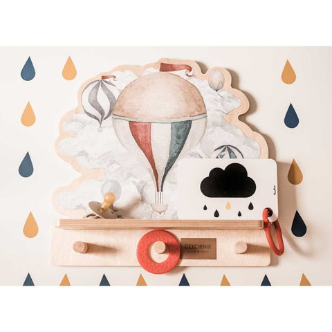 4. Mini wall shelf with hot air balloon design on patterned wall, displaying a pacifier, teething ring, and card