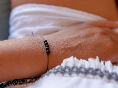 1. Women's minimalist lava stone bracelet by Canary Lava worn on wrist, showcasing adjustable design and natural elegance