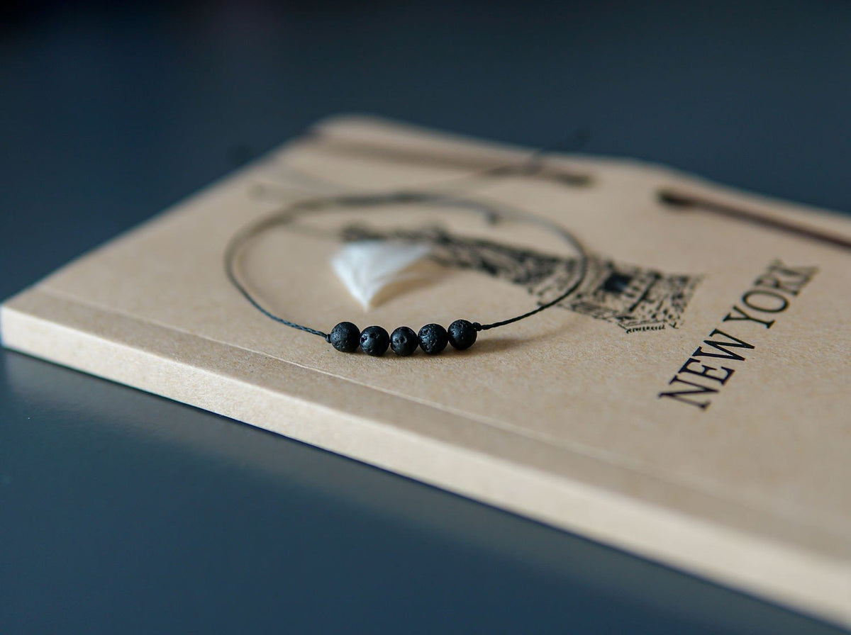 3. Close-up of Canary Lava minimalist lava stone bracelet on New York-themed notebook, highlighting volcanic beads