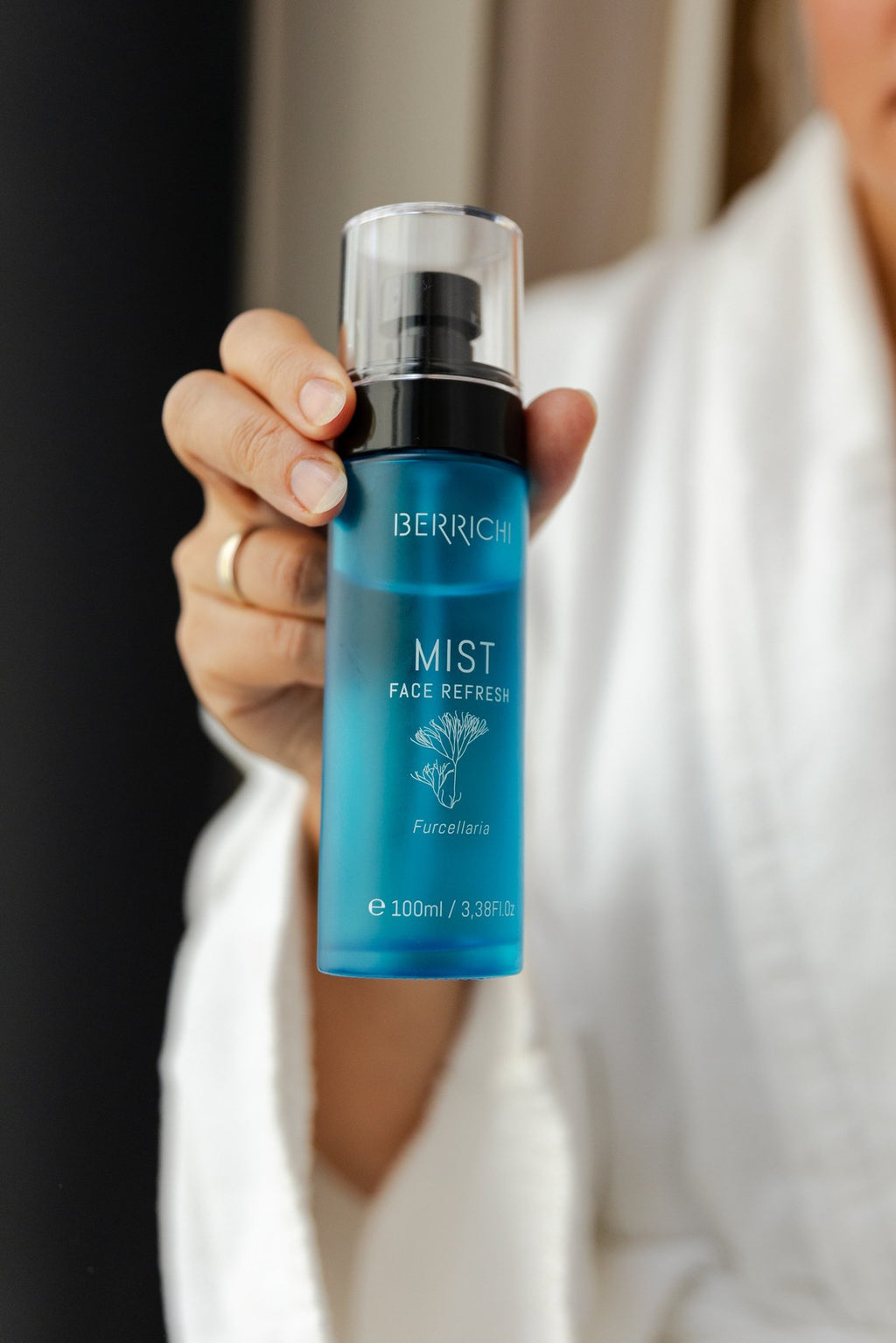 2. Woman in white robe displaying Berrichi MIST Face Spray, highlighting skincare routine