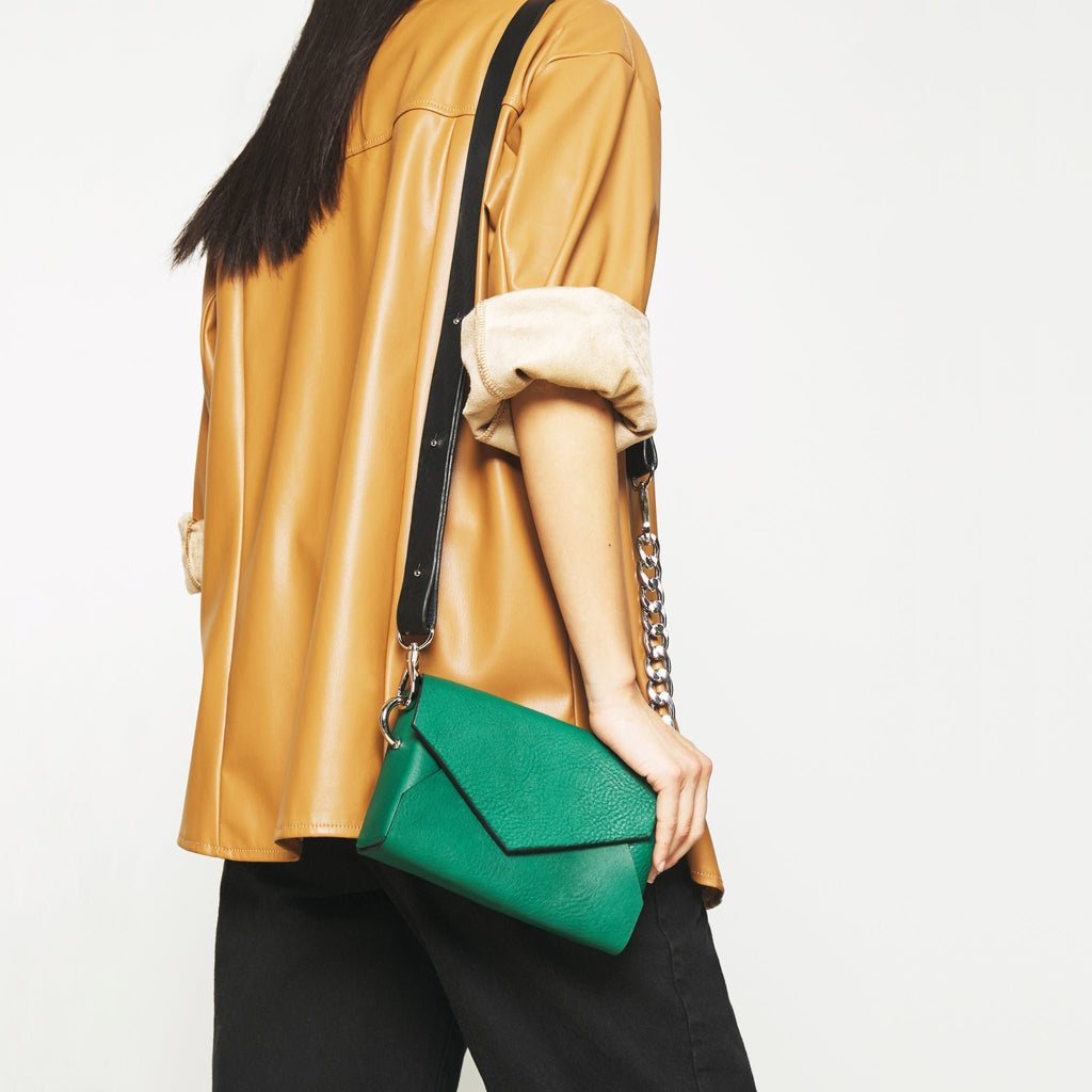 1. Woman wearing Daz Studio green leather envelope bag crossbody with black strap and chain detail