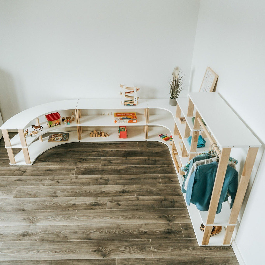5. Top view of a playroom with modular Montessori shelves in white and natural wood, displaying toys and clothes