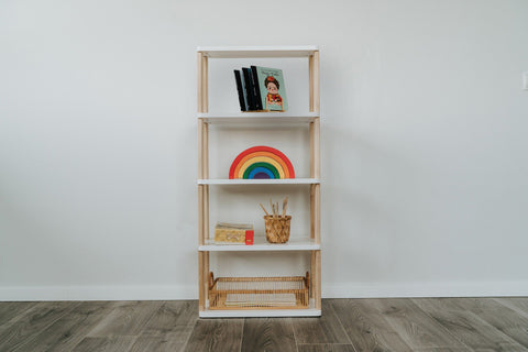 1. Modular Montessori Shelf Straight Mini with five shelves displaying books, a rainbow toy, and art supplies against a white wall on wooden flooring