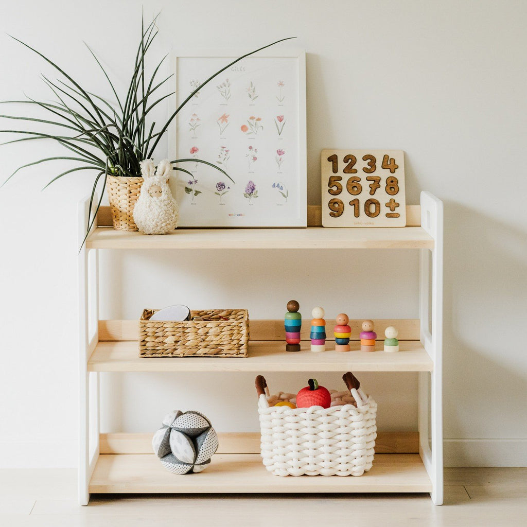 1. Montessori toy shelf with toys and decor in a children's room, featuring a white and natural wood finish