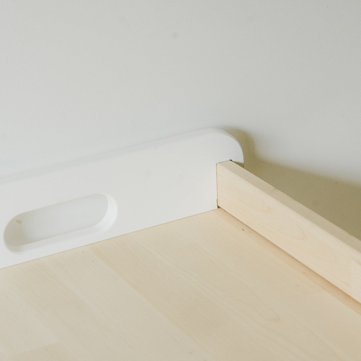 7. Close-up of the corner detail of a Montessori toy shelf, showing white and natural wood finish