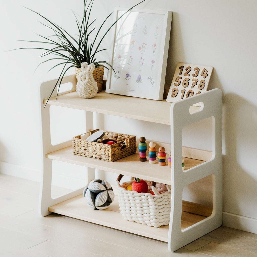 4. Montessori toy shelf with toys and decor, featuring a white and natural wood finish in a children's room